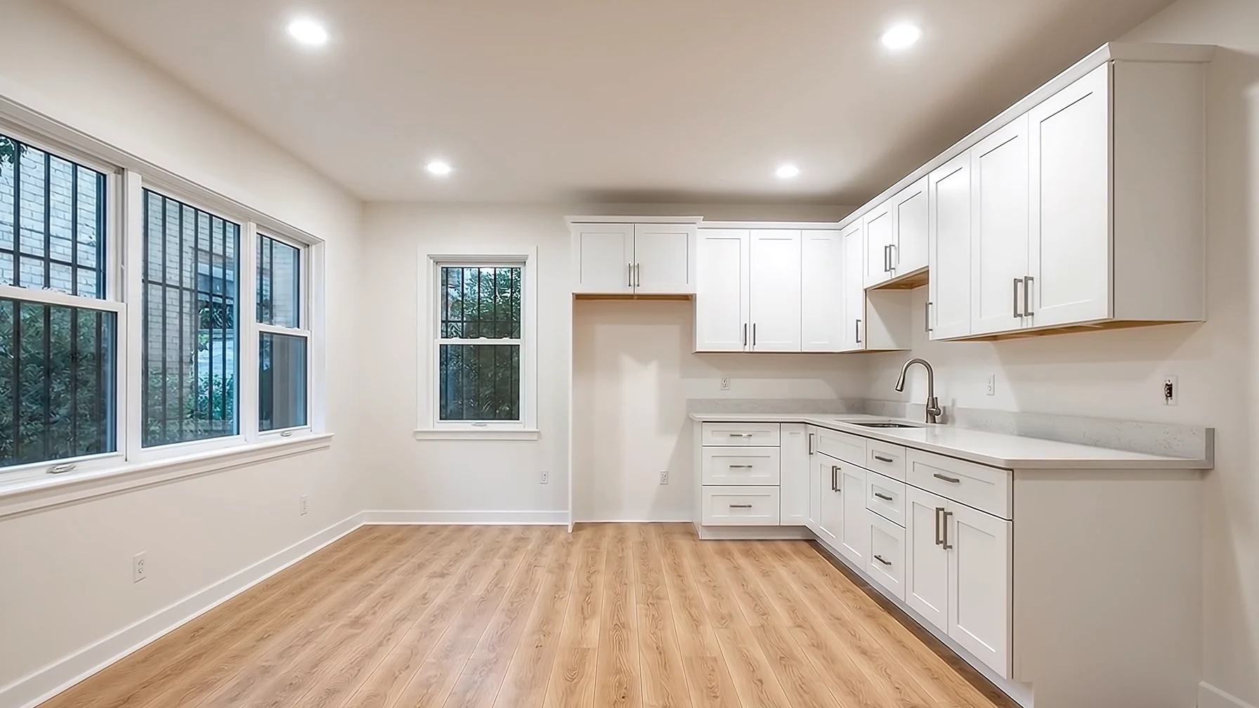 An old kitchen with damp-stained walls and worn cabinets, renovated into a white shaker kitchen with a wooden floor